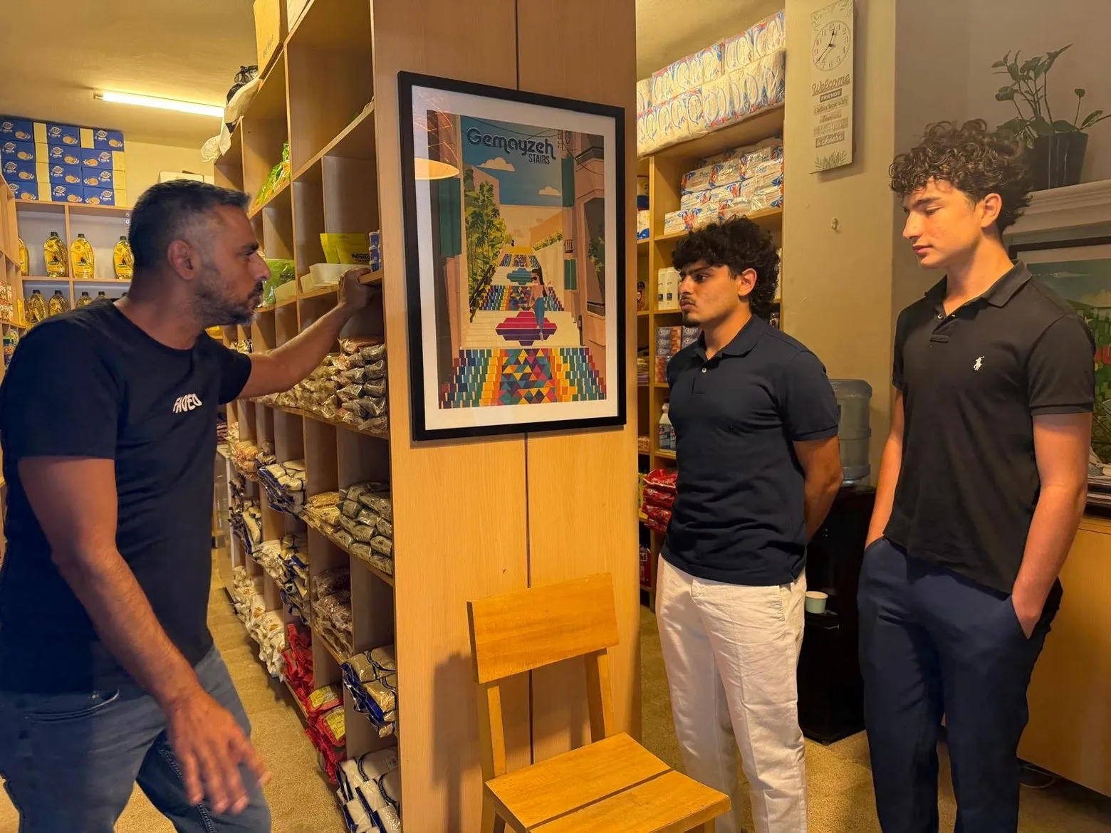Two students talk with a Beit el Baraka team member between shelves of food and supplies.